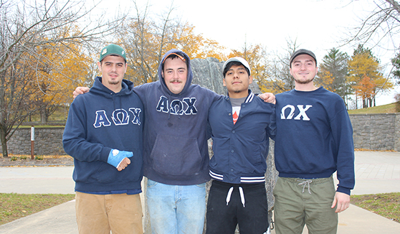 AOX Fraternity poses in front of the Campus Plaza rock.