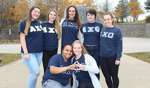 AXO Sorority poses in front of the Campus Plaza rock.