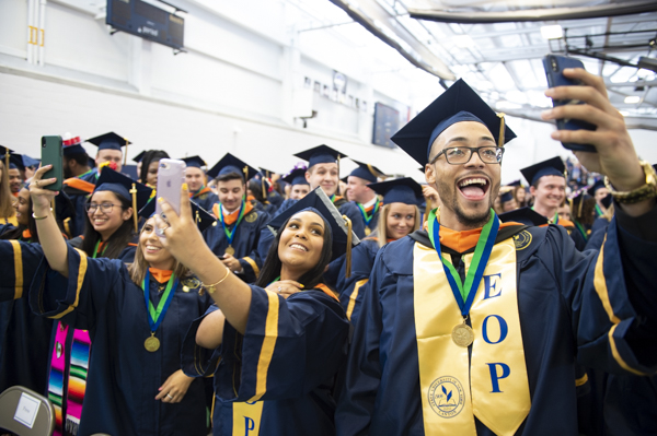 A group of graduates take selfies at SUNY Canton's commencement ceremony