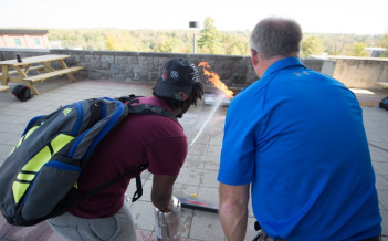A student is trained on proper fire extinguisher use in the campus plaza.