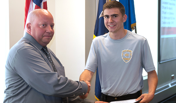 Rodney Votra shakes hands with cadet Jesse Walley at the Corrections graduation ceremony.