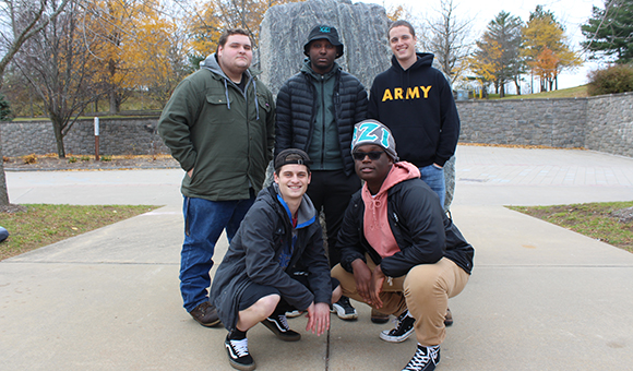 YZI Fraternity poses in front of the Campus Plaza rock.