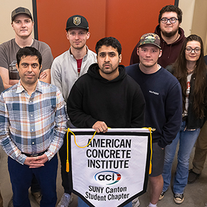 The ACI student chapter holds up their banner in the concrete testing lab.