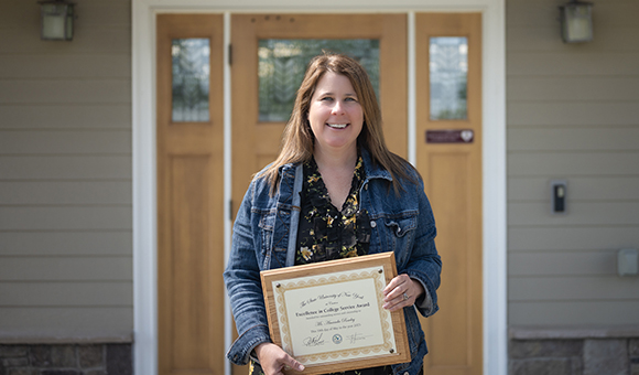 Amanda Rowley holds her Excellence in College Service Award outside Halford Hall.