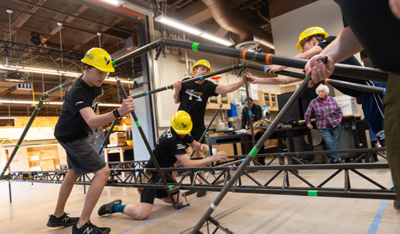 Students doing a trial run of a steel bridge build.