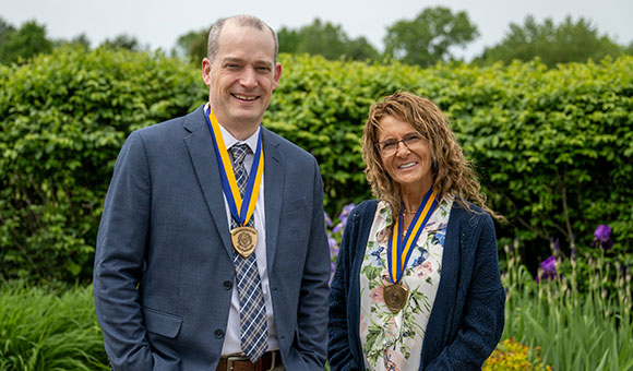Travis Smith and Shelly Thompson stand outside French Hall with their Chancellor's medallions.
