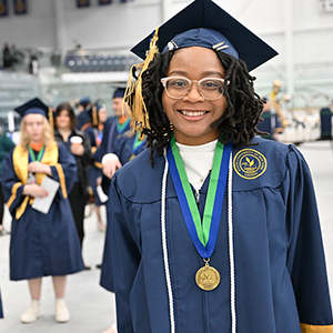 A graduate poses for a photo in the ice arena prior to Commencement.
