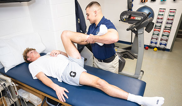 Connor Dickinson helps Finance major Nolan Sullivan stretch in the Physical Therapist Assistant lab.