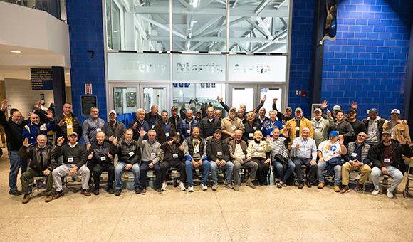 SUNY Canton alumni, friends, and family join Terry Martin in front of the new Terry Martin Arena signage.