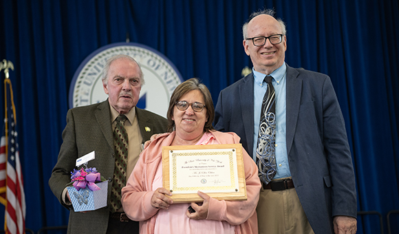 JoEllen Oshier accepts the Presidential Meritorious Service Award from Ronald O'Neill and President Szafran.