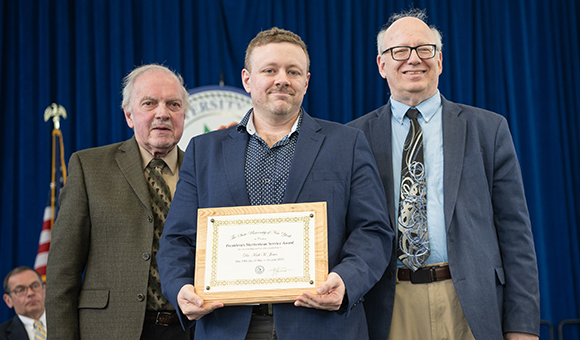 Kirk Jones accepts the Presidential Meritorious Service Award from Ronald O'Neill and President Szafran.