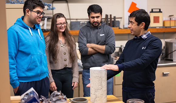 Saeid Haji Ghasemali showcases a concrete cylinder as students look on.