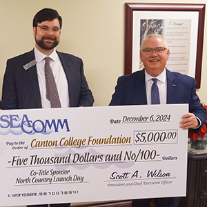 Geoffrey C.S. VanderWoude holding a donation check with SeaComm President & CEO Scott Wilson