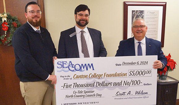 Christopher Chambers and Geoffrey C.S. VanderWoude holding a donation check with SeaComm President & CEO Scott Wilson