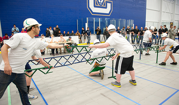 Students assemble a steel bridge during a competition in the Roos House Athletic Center