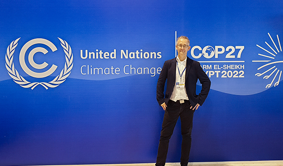 Thomas Ackermann stands in from the United Nations Climate Change conference banner.