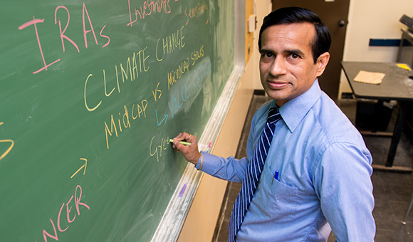Umesh Kumar writes on a chalkboard