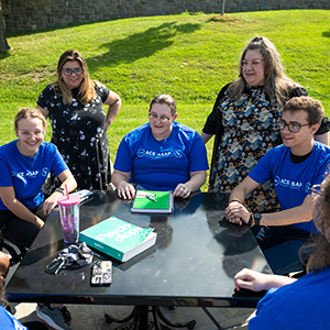 ASAP and ACE students sit at a table outside Dana Hall with Kelsey Guerard and Amber Daby.