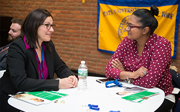 Professor Marela Fiacco sits at a table with an alumna.