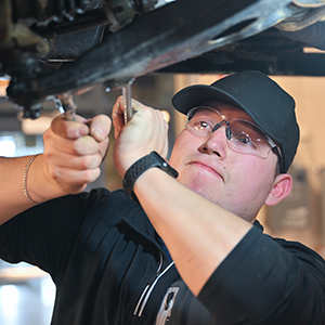 Byron Amaya removes a sway bar link on a Subaru in the Automotive Tech lab.