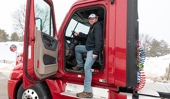 Ryan Harrigan sits in the new red Freightliner truck.