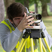 A student looks through surveying equipment.