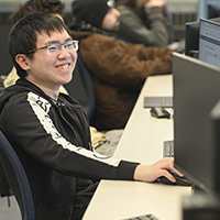 A smiling student works in the Computer Information Systems lab.