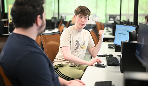 Two students converse in the IT computer lab.