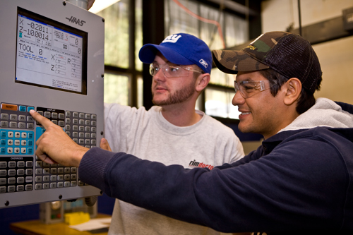 Two students use a CNC machine.