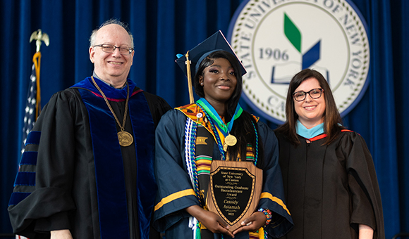 Cassidy Asiamah is awarded Outstanding Graduate by President Szafran and VP Courtney Bish.