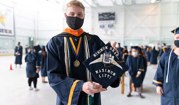 Andrew Fitch holds up his cap that says, 