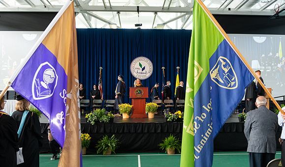 School flags hang as the stage party enters Commencement 2022.