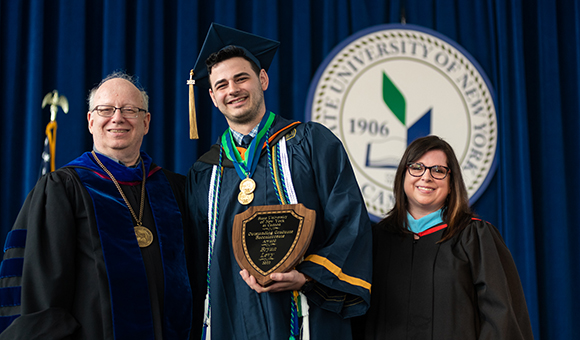 Bryan Levy is awarded Outstanding Graduate by President Szafran and VP Courtney Bish.