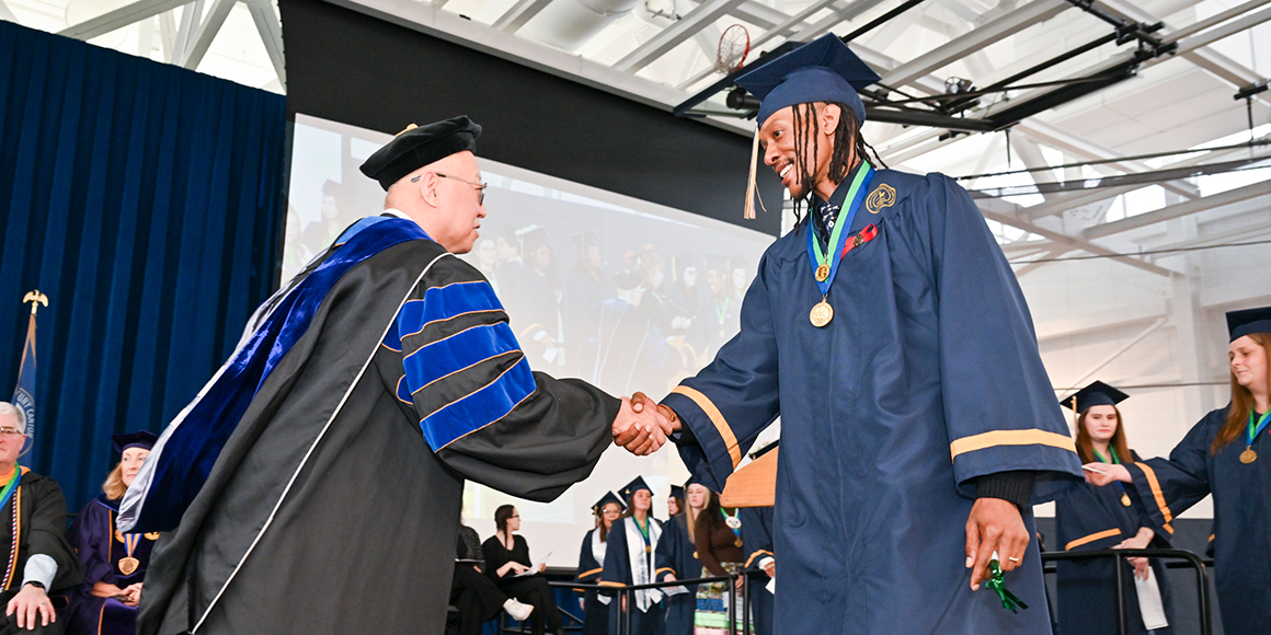 Dean Ken Rhee shakes hands with graduate Lonneil Simpson.