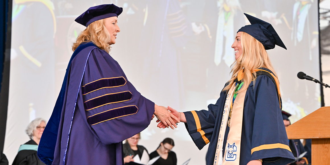Dean Michele Snyder shakes hands with Sydney Valiquette during Commencement.