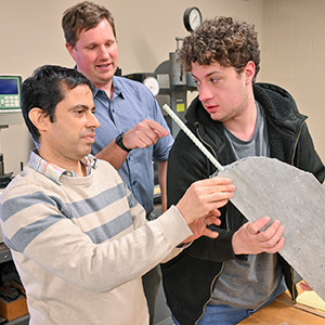 Saied Haji Ghasemali, Brett Miller, and Seth Thomas inspect a concrete sample.