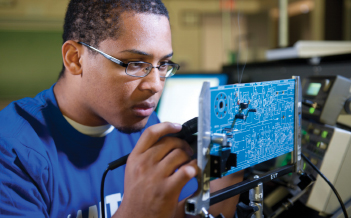 A student solders a motherboard