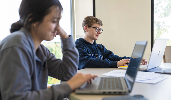 Two Data Science students process data on laptops.