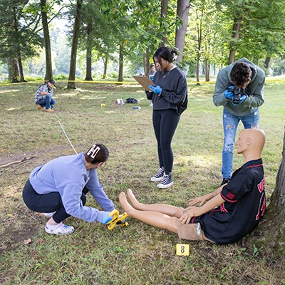 Students collect evidence at wooded mock crime scene.