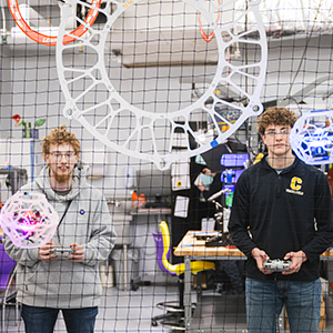 Two Madrid-Waddington students fly brightly lit drones into circular soccer goals.