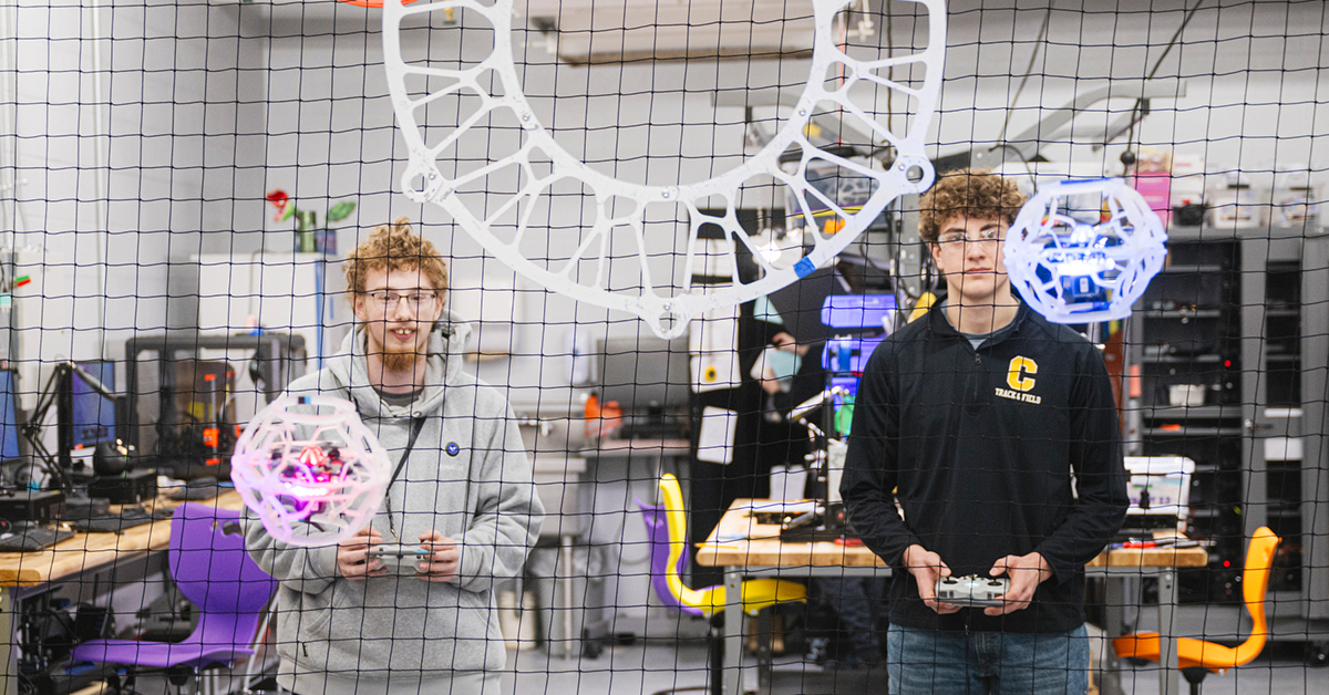 Two Madrid-Waddington students fly brightly lit drones into circular soccer goals.