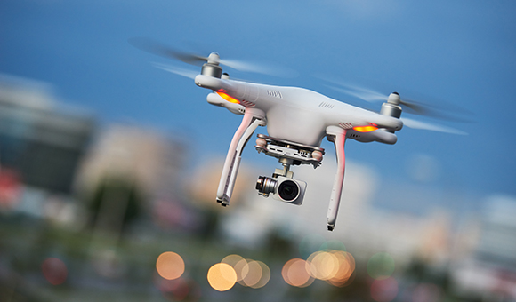 A drone flies though a blue sky.