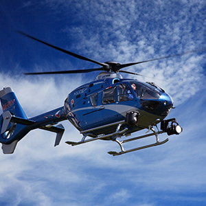 An emergency helicopter flies through a blue sky.