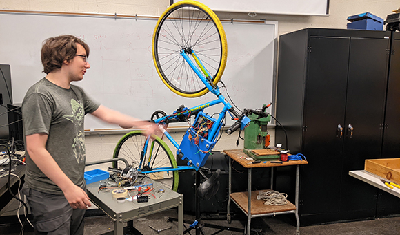 A student showcases an electric bike during ELEC 477 course.