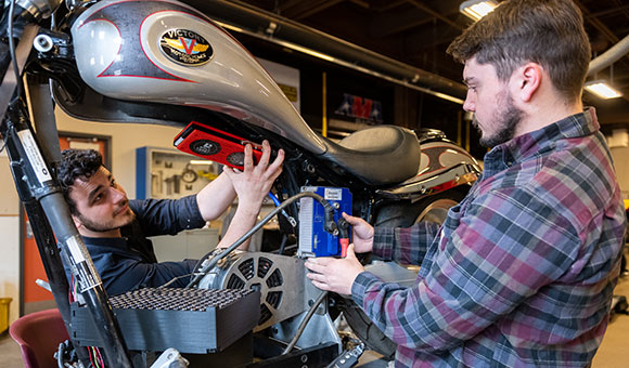 Two students work on an electric motorcycle prototype.