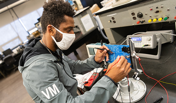 Van Moussavou builds a radio from a circuit board in Nevaldine Hall.