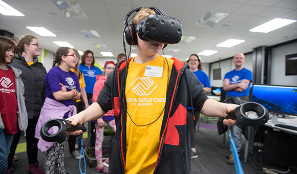 A student wears virtual reality goggles at Engineer's Week while classmates look on.