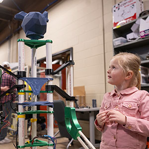 A student looks at a robotic prototype during the Engineer's Week Open House.