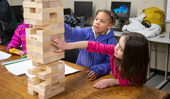 Two young students play Jenga during Engineer's Week Open House.