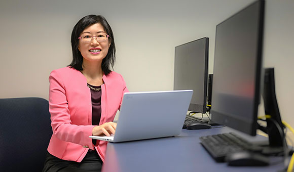 Eunjyu Yu sits in a classroom with a laptop.